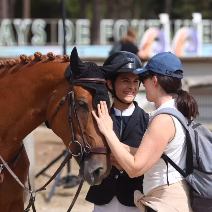 Cavalier félicité à côté de son cheval bai en concours